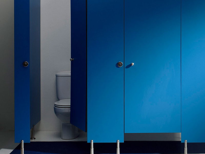 Cabinas fenólicas azules de aseo con banco de vestuario delante