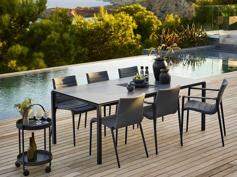 Mesa de exterior Cane-line Pure junto a una piscina